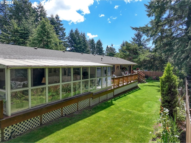 rear view of property with fence, a wooden deck, roof with shingles, a yard, and a sunroom