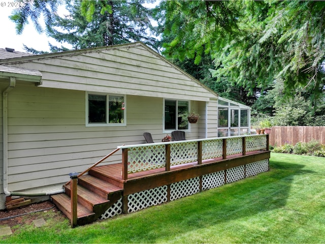 rear view of house with a lawn, a deck, and fence