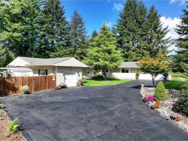 single story home featuring aphalt driveway, a front lawn, an attached garage, and fence