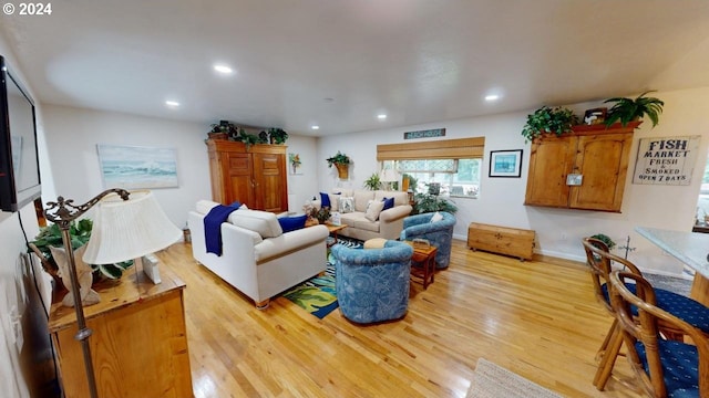 living room featuring recessed lighting, baseboards, and light wood finished floors