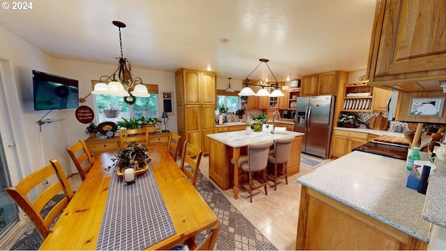 interior space with a chandelier, a center island with sink, light stone counters, stainless steel refrigerator with ice dispenser, and a sink