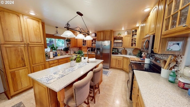 kitchen featuring a breakfast bar area, brown cabinetry, a center island with sink, appliances with stainless steel finishes, and tasteful backsplash