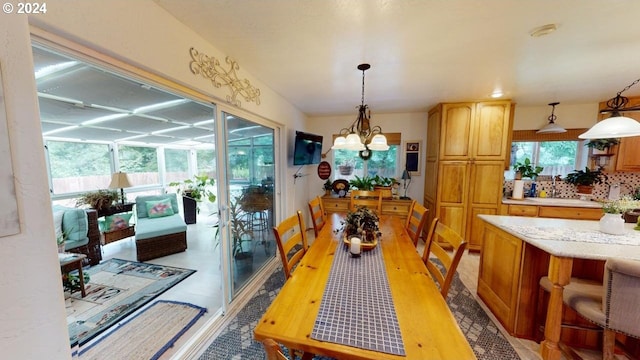 dining space featuring an inviting chandelier, light wood-style floors, and a sunroom