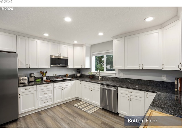 35165 Rueppell Ave, Pacific City, OR 97135 - kitchen featuring stainless steel appliances, a sink, white cabinetry, light wood-style floors, and recessed lighting