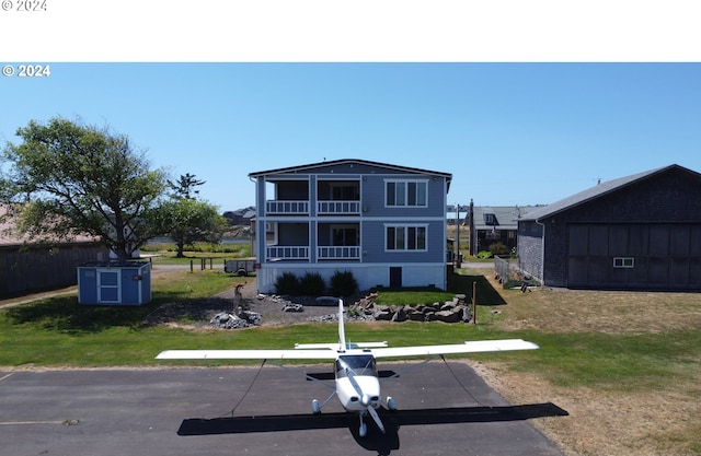 view of front of property with a balcony, a front yard, and a shed