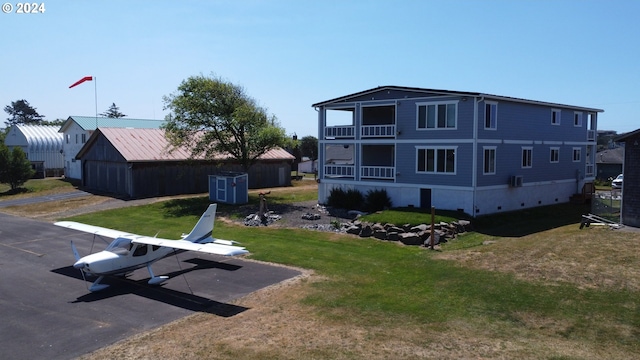 exterior space featuring a balcony, a storage unit, and a lawn