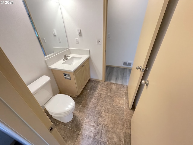 half bath with toilet, baseboards, visible vents, and vanity