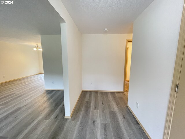 hallway featuring a textured ceiling, hardwood / wood-style floors, and a chandelier