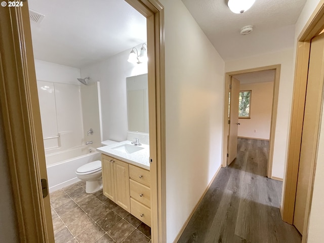 bathroom with toilet, wood finished floors, visible vents, vanity, and shower / bathing tub combination