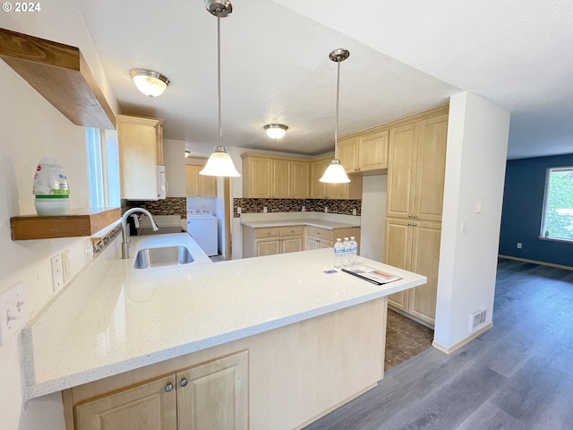 kitchen with light brown cabinetry, sink, kitchen peninsula, and washer / dryer