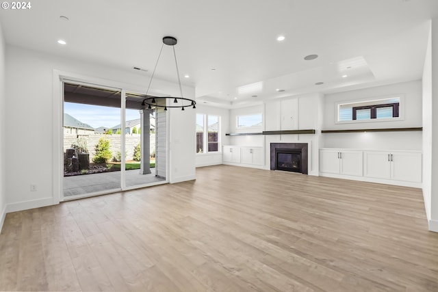 unfurnished living room featuring a raised ceiling and light wood-type flooring