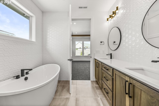 bathroom featuring double sink vanity, tile floors, tile walls, backsplash, and a bathing tub