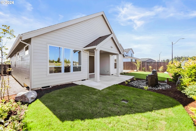 back of property with a yard and a patio area