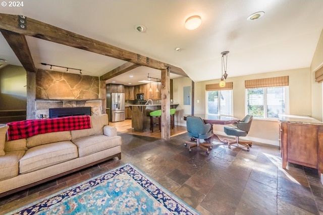 living room featuring a stone fireplace and beamed ceiling