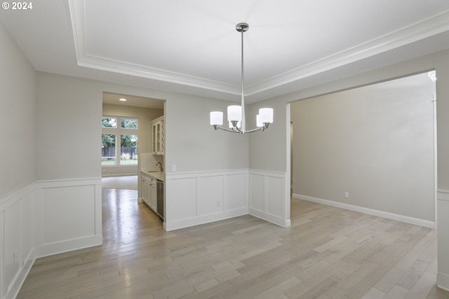 unfurnished dining area featuring light wood-type flooring, a tray ceiling, and a chandelier