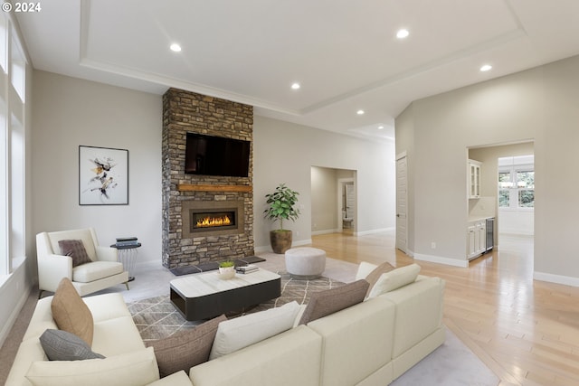 living room with a fireplace, a tray ceiling, and light hardwood / wood-style floors