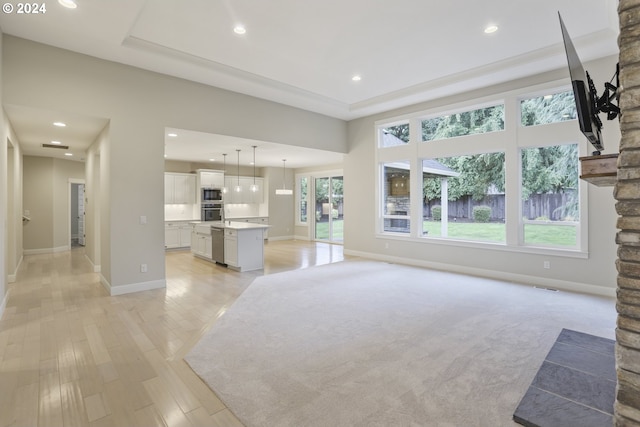 unfurnished living room featuring light colored carpet and a tray ceiling