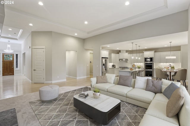 living room with a tray ceiling, dark wood-type flooring, a towering ceiling, and sink