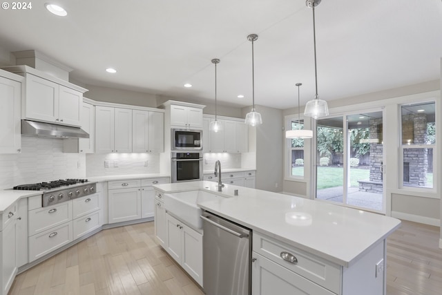 kitchen featuring appliances with stainless steel finishes, white cabinetry, tasteful backsplash, and light hardwood / wood-style flooring