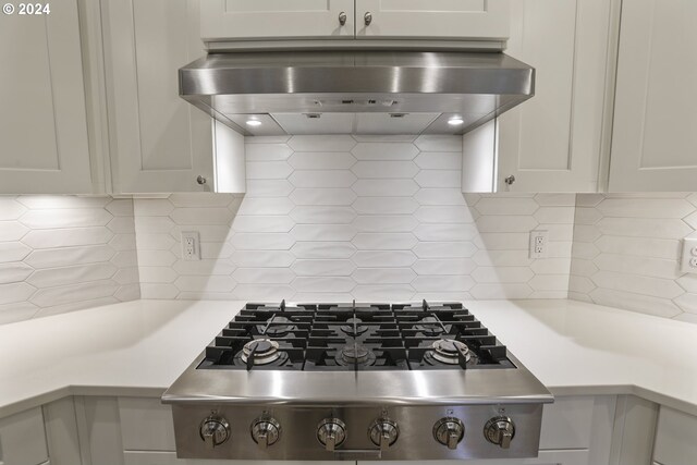 kitchen with white cabinets, wall chimney exhaust hood, stainless steel gas stovetop, and decorative backsplash