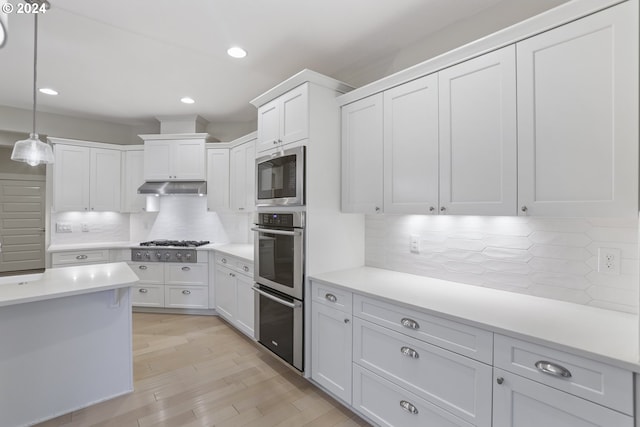 kitchen with stainless steel appliances, decorative light fixtures, backsplash, and light hardwood / wood-style floors