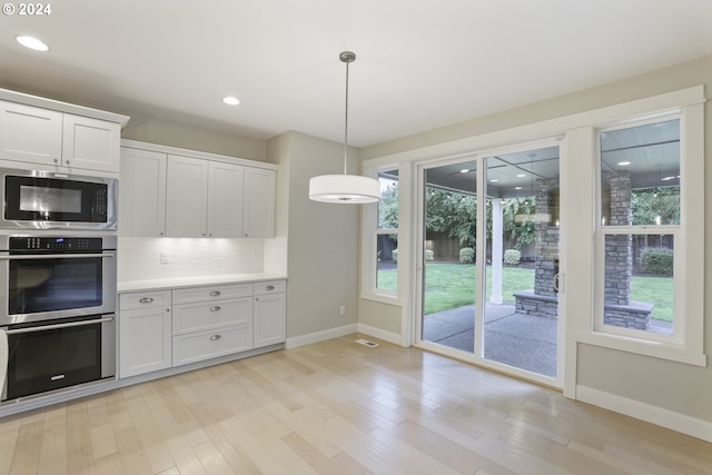 kitchen with light wood-type flooring, white cabinetry, decorative light fixtures, stainless steel appliances, and decorative backsplash