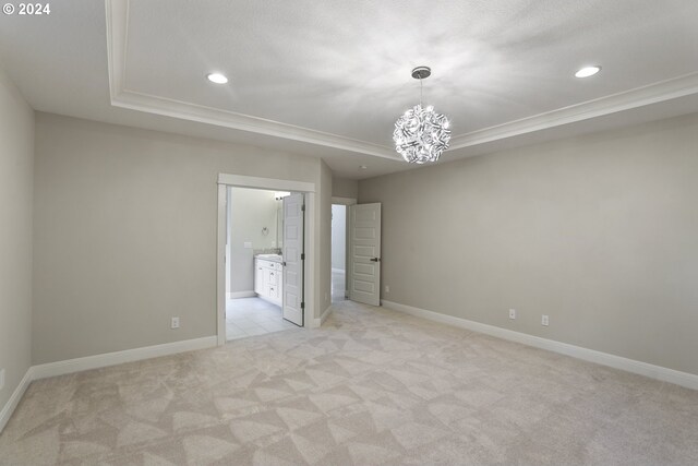 unfurnished room featuring a tray ceiling, light tile patterned floors, and a chandelier