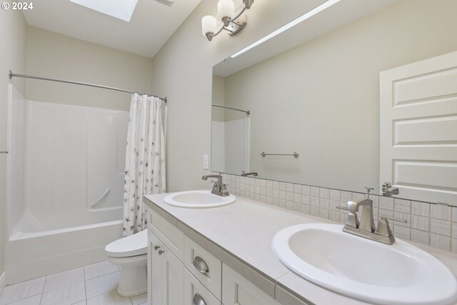 full bathroom featuring toilet, tile patterned flooring, vanity, a skylight, and shower / bath combo