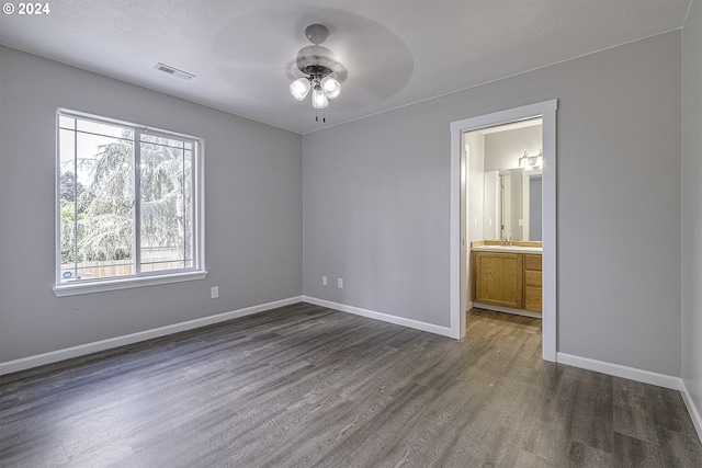 unfurnished bedroom featuring dark hardwood / wood-style flooring, ensuite bathroom, ceiling fan, and sink