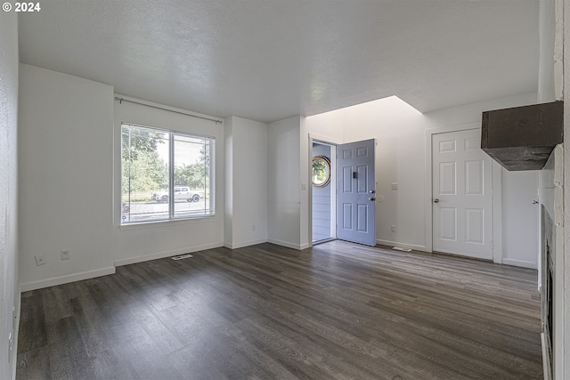 unfurnished living room with dark hardwood / wood-style floors and a textured ceiling