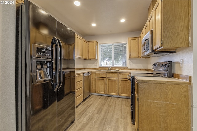 kitchen featuring light brown cabinetry, sink, black appliances, and light wood-type flooring