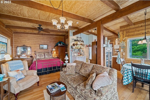 living room with beamed ceiling, light wood-type flooring, wooden walls, and a healthy amount of sunlight