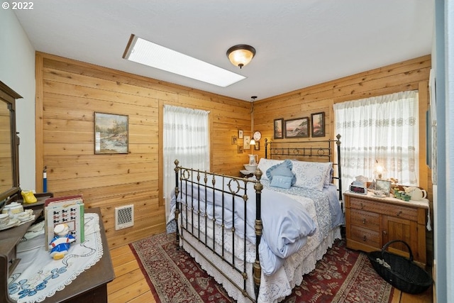 12880 Hobsonville Point Dr, Bay City, OR 97107 - bedroom with multiple windows, wood walls, wood finished floors, and a skylight