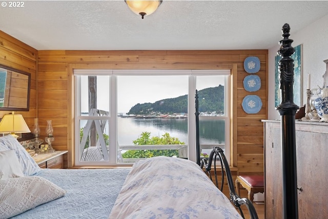 12880 Hobsonville Point Dr, Bay City, OR 97107 - bedroom with a textured ceiling, wooden walls, and a water view