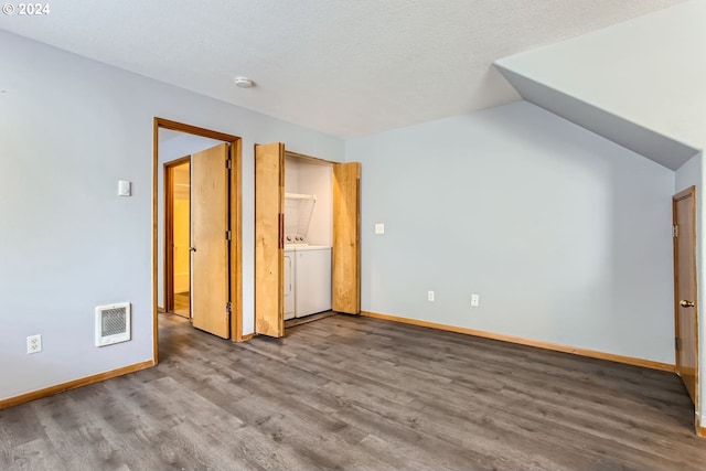 unfurnished bedroom featuring washer / clothes dryer, wood-type flooring, vaulted ceiling, and a textured ceiling