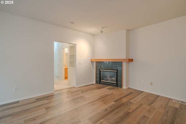 unfurnished living room featuring a fireplace, visible vents, baseboards, and light wood-style flooring