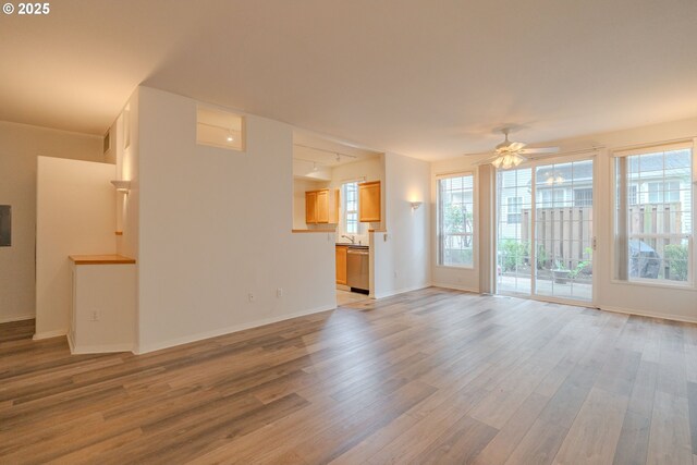 unfurnished living room featuring light wood-style floors, ceiling fan, and baseboards
