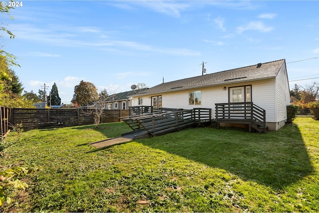 rear view of property featuring a deck and a lawn