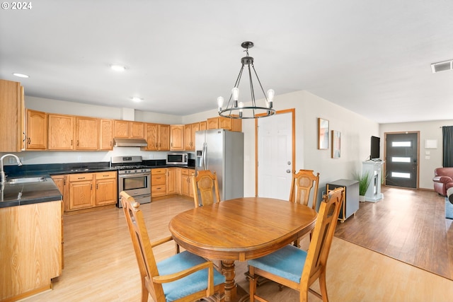 kitchen featuring sink, stainless steel appliances, a notable chandelier, pendant lighting, and light hardwood / wood-style floors