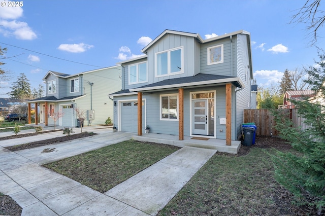 view of front facade featuring an attached garage, board and batten siding, a front yard, fence, and driveway