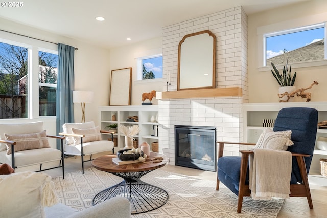 living area with a brick fireplace, light wood finished floors, and recessed lighting