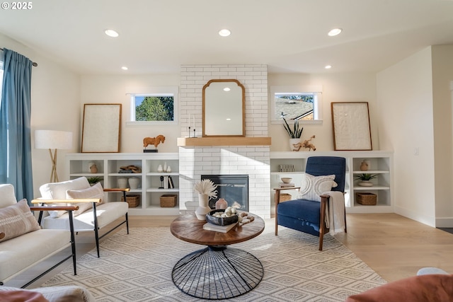 living area with recessed lighting, a brick fireplace, light wood-style flooring, and baseboards