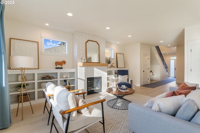 living area with a brick fireplace, light wood-style flooring, and recessed lighting