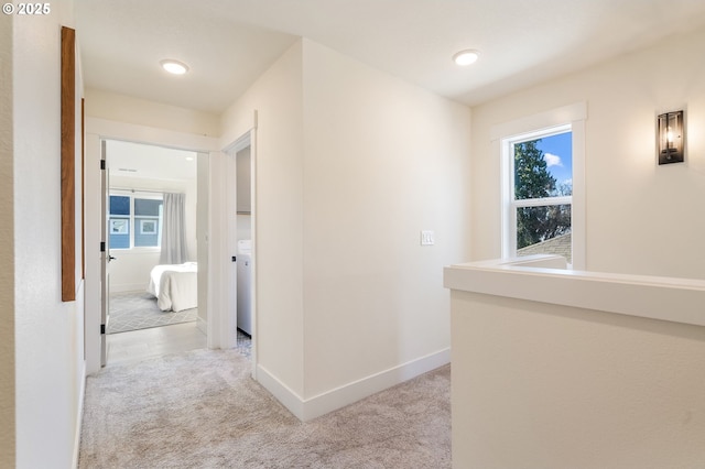 corridor featuring light colored carpet and baseboards