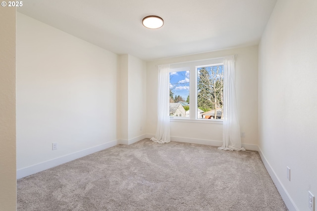 spare room with baseboards and light colored carpet