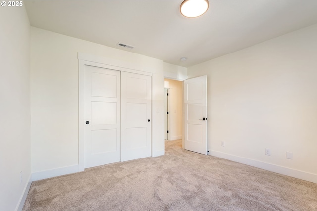 unfurnished bedroom featuring light carpet and a closet