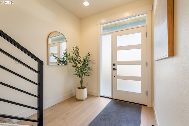 foyer with light wood-type flooring, plenty of natural light, stairs, and baseboards