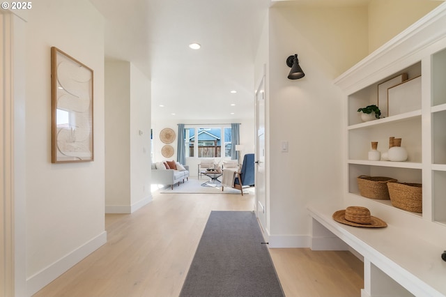 corridor featuring baseboards, built in shelves, recessed lighting, and light wood-style floors