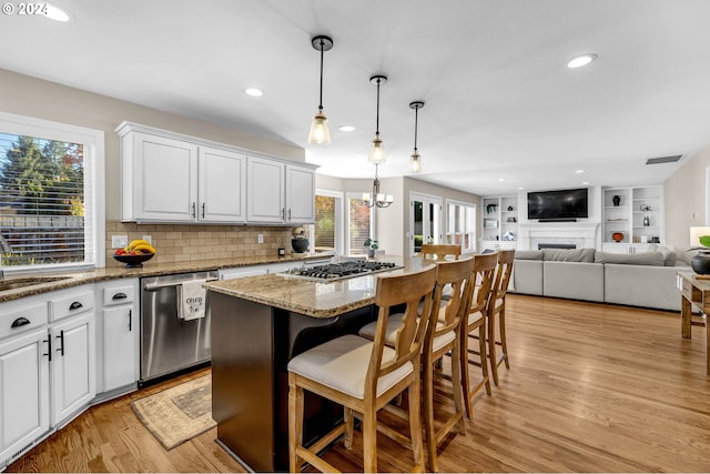 kitchen with a kitchen breakfast bar, stainless steel appliances, light hardwood / wood-style flooring, white cabinets, and a kitchen island