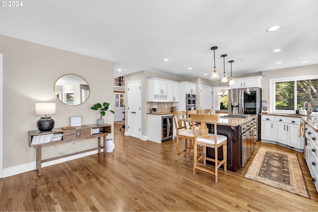 kitchen featuring a center island, stainless steel appliances, light hardwood / wood-style floors, a breakfast bar, and white cabinets